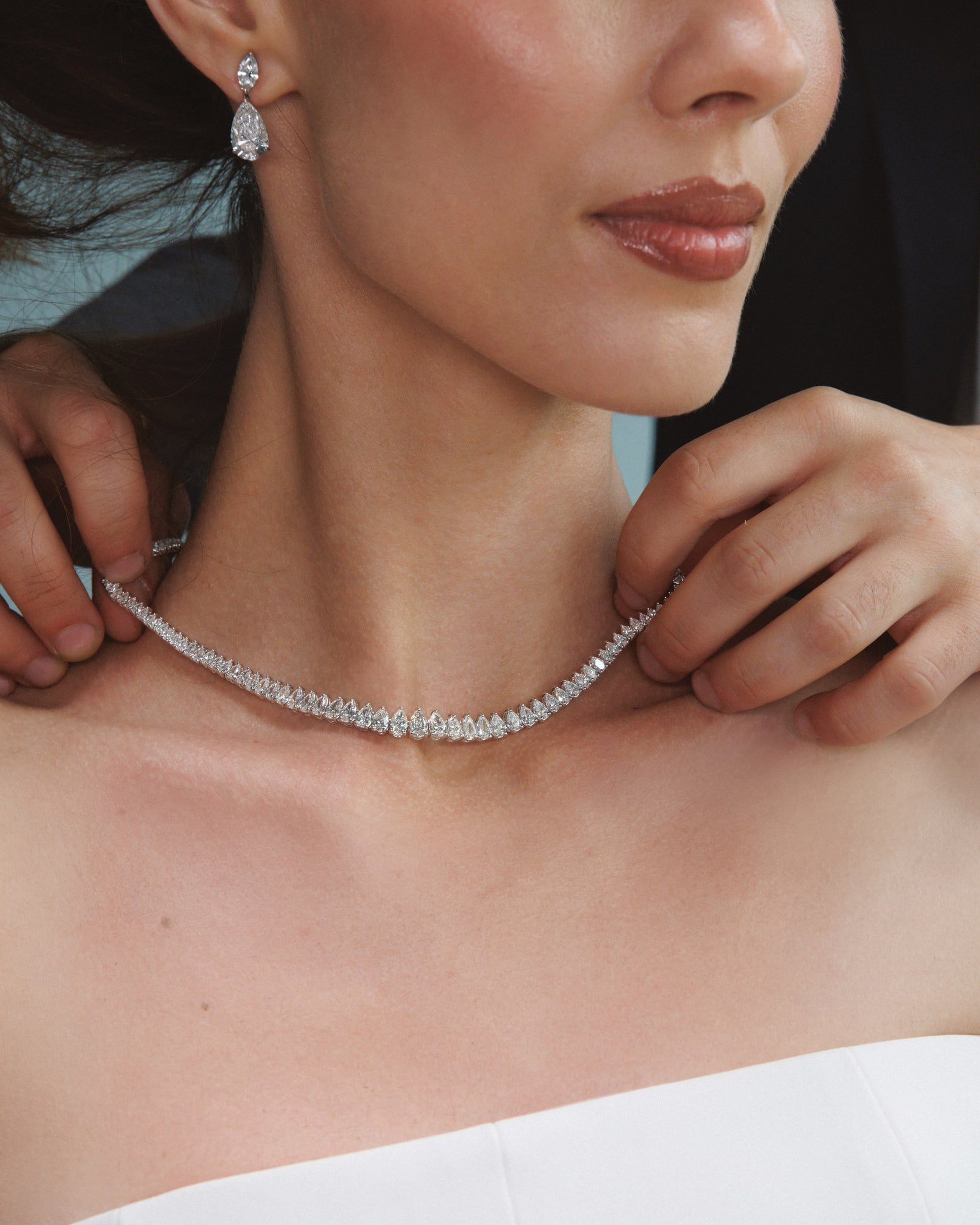 She touches the necklace at her throat.