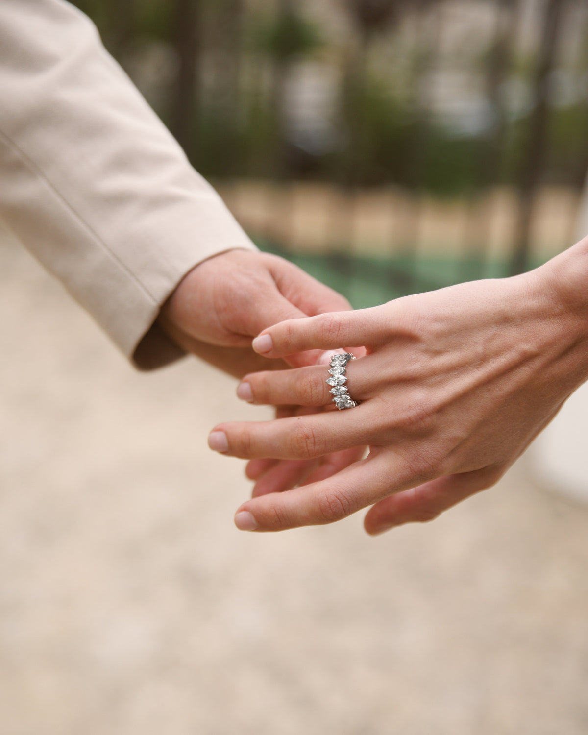Two hands loosely joined, a diamond band on her finger.