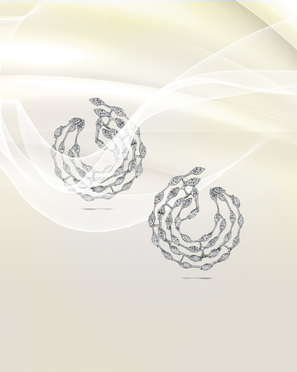 A pair of diamond hoop earrings on ivory silk.