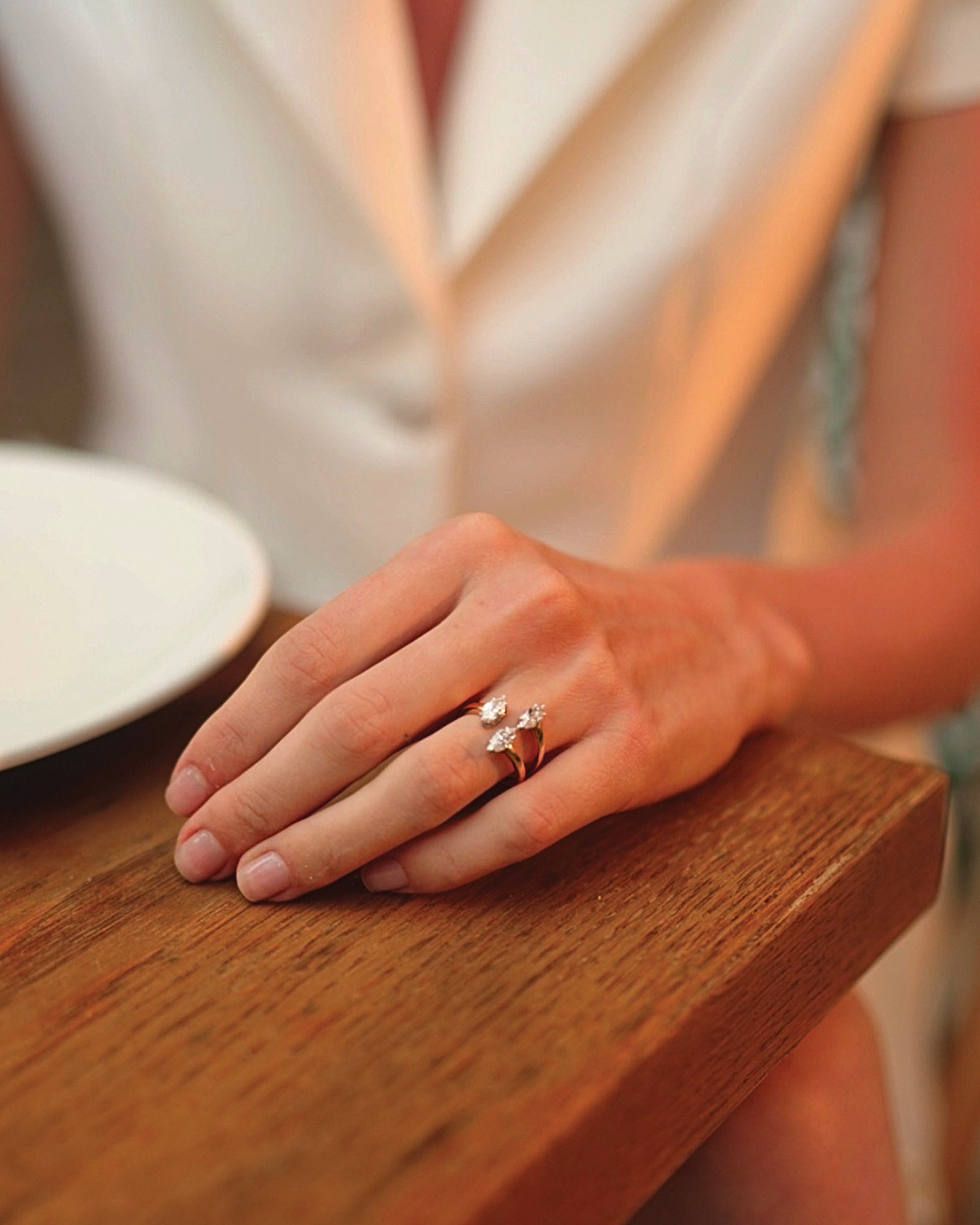 Her hand rests on the table, the ring on her finger.