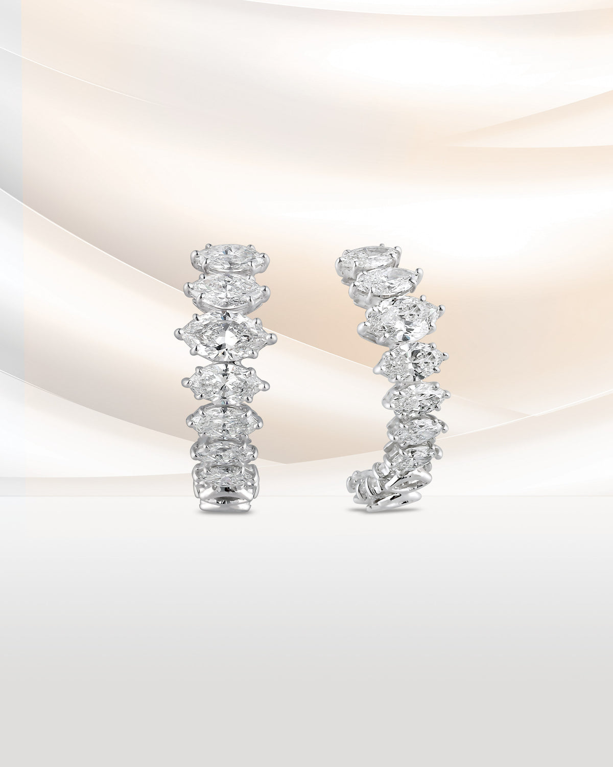 A pair of diamond hoop earrings on blush silk.
