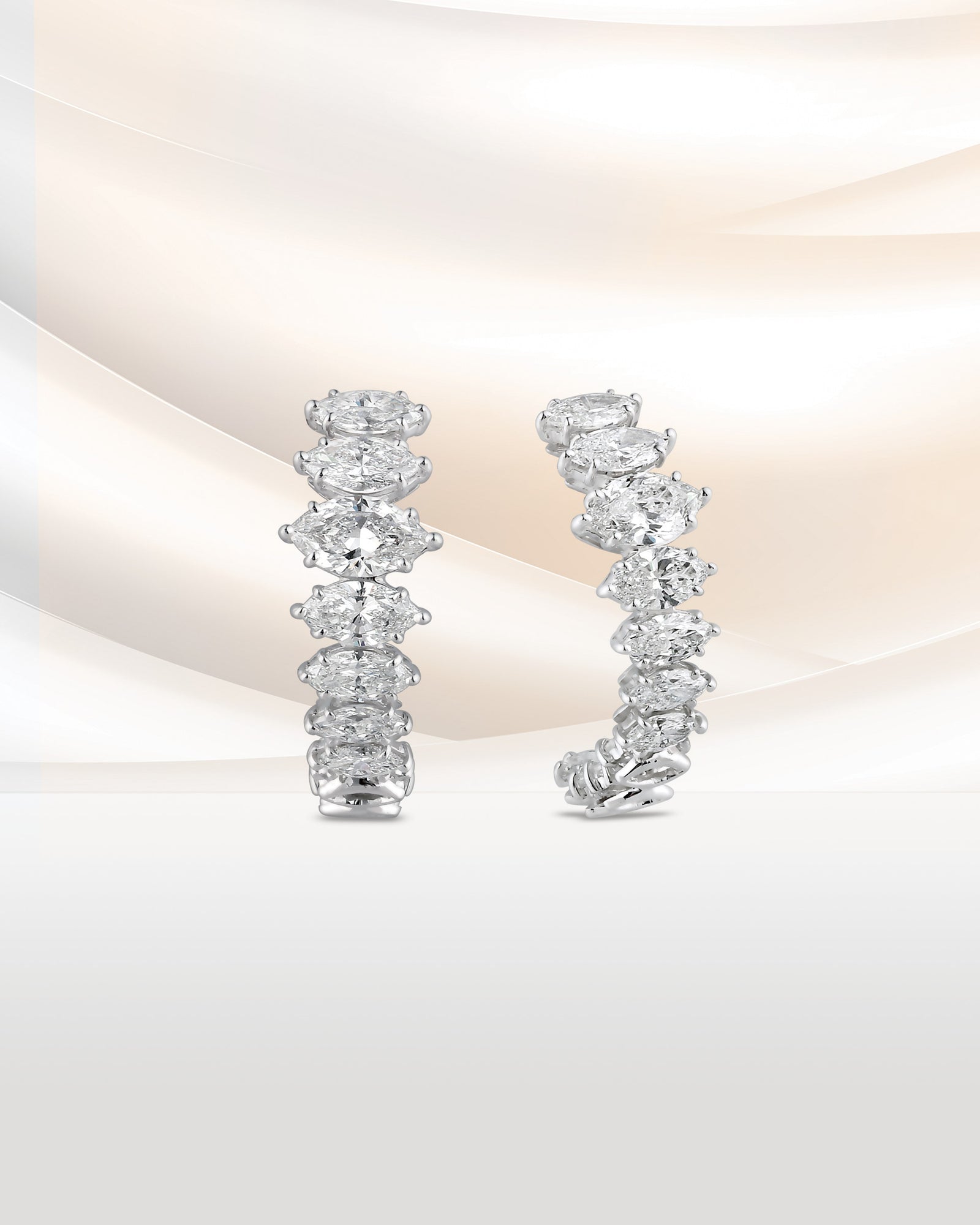 A pair of diamond hoop earrings on blush silk.
